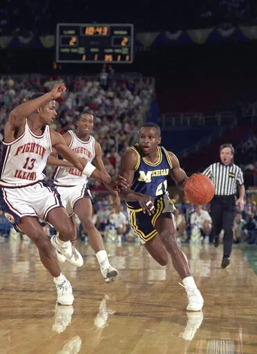 Michigan guard Rumeal Robinson (21) works the ball past Illinois guard Kendall Gill (13) during first half of a semifinal in the NCAA men's college basketball tournament Final Four on April 1, 1989, in Seattle. After 33 lead changes, it was tied at 81 when Sean Higgins scored off an offensive rebound in the final seconds to send the Wolverines to the final. (AP Photo/Susan Ragan, File)