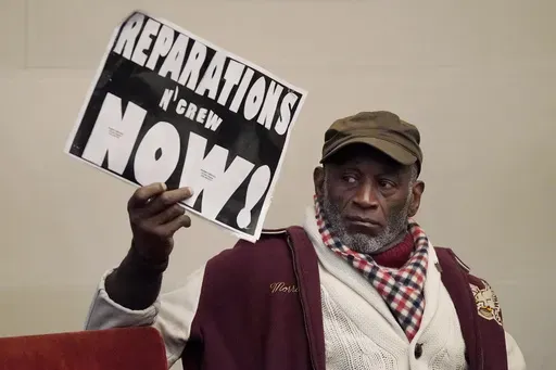 Morris Griffin holds up a sign during a meeting by the Task Force to Study and Develop Reparation Proposals for African Americans in Oakland, Calif., Dec. 14, 2022. (AP Photo/Jeff Chiu, File)