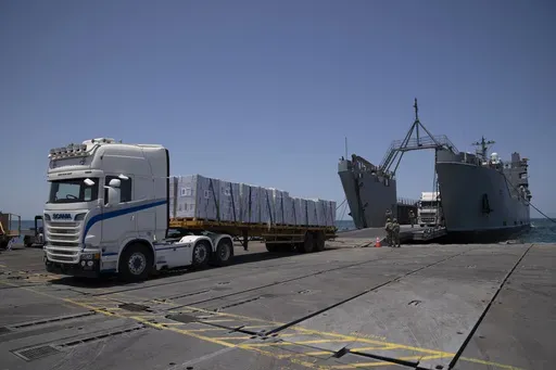 U.S. Army soldiers stand next to trucks arriving loaded with humanitarian aid at the U.S.-built floating pier Trident before reaching the beach on the coast of the Gaza Strip, Tuesday, June 25, 2024. (AP Photo/Leo Correa)