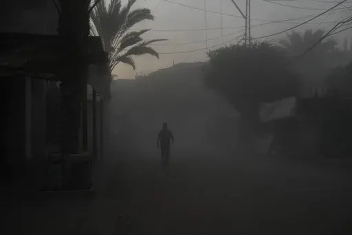 A Palestinian walks on a smoke-filled street after an Israeli airstrike in Deir al Balah, Gaza Strip, Tuesday, Aug. 6, 2024. (AP Photo/Abdel Kareem Hana)