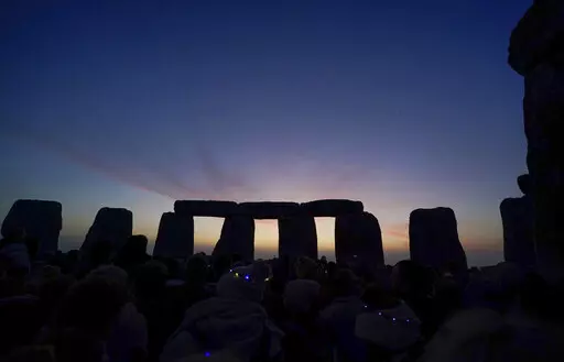 Dawn breaks behind the stones during the Summer Solstice festivities at Stonehenge in Wiltshire, England, Tuesday, June 21, 2022. After two years of closure due to the COVID-19 pandemic, Stonehenge reopened Monday for the Summer Solstice celebrations. (Andrew Matthews/PA via AP)