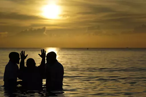 Louis "Jerry" Barrios, second from left, reacts after being baptized by Co-Pastors Rev. Brian Glasford, right, and his brother Rev. Jason Glasford, left, in the Atlantic Ocean during an Easter sunrise service with the New Life Missionary Baptist Church, Sunday, April 9, 2023, in Miami Beach, Fla. (AP Photo/Wilfredo Lee)