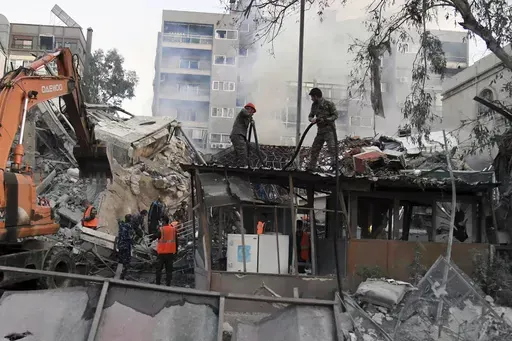In this photo released by the official Syrian state news agency SANA, emergency service workers clear the rubble at a destroyed building struck by Israeli jets in Damascus, Syria, Monday, April 1, 2024. An Israeli airstrike has destroyed the consular section of Iran's embassy in Syria, killing a senior Iranian military adviser and roughly a handful of other people, Syrian state media said Monday. (SANA via AP)
