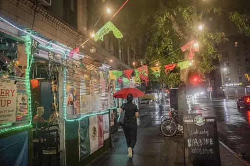 A restaurant's pandemic-era outdoor dining, left, extends onto a sidewalk in Brooklyn's Flatbush neighborhood, Monday Aug. 7, 2023, in New York. New York City's roadway dining sheds, a pandemic innovation, are coming under new rules for design and seasonality. (AP Photo/Bebeto Matthews)