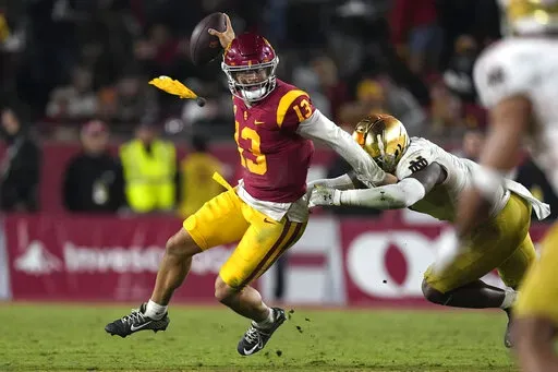 Southern California quarterback Caleb Williams, left, escapes a tackle by Notre Dame defensive lineman Justin Ademilola as a flag is thrown on the play during the second half of an NCAA college football game Saturday, Nov. 26, 2022, in Los Angeles. (AP Photo/Mark J. Terrill)