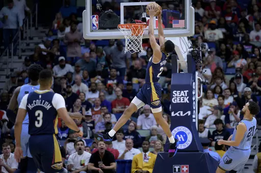 New Orleans Pelicans guard Trey Murphy III (25) dunks next to Memphis Grizzlies guard Tyus Jones (21) during the first half of an NBA basketball game in New Orleans, Wednesday, April 5, 2023. (AP Photo/Matthew Hinton)