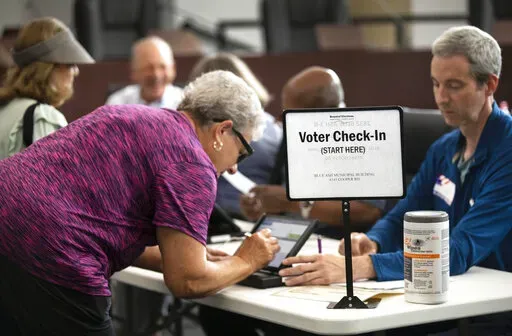 A poll worker prepares to give a ballot to a voter at the Blue Ash, Ohio Municipal building for the primary, Aug. 2, 2022. A bipartisan effort among states to combat voter fraud has found itself in the crosshairs of conspiracy theories fueled by Donald Trump’s false claims about the 2020 presidential election and now faces an uncertain future. (Liz Dufour/The Cincinnati Enquirer via AP, File)