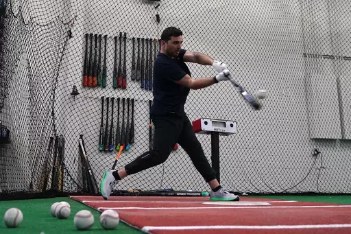 A batter takes a swing inside a batting cage at the Driveline facility in Scottsdale, Ariz., Thursday, Feb. 16, 2023. The batting information is read by a sensor device just to the right of the batter and the information is projected onto the screen in a different part of the cage area. (AP Photo/Ross D. Franklin)