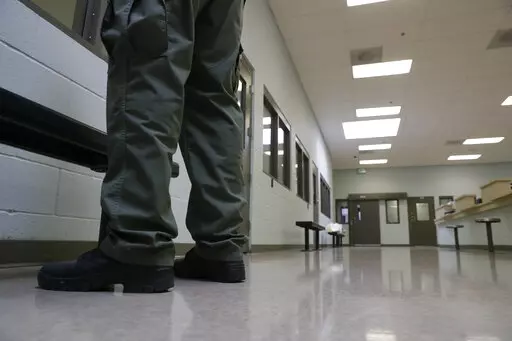 In this Aug. 28, 2019, photo, a guard stands in the intake area at the Adelanto ICE Processing Center in Adelanto, Calif. In a wind-whipped California desert town, a sprawling facility can house nearly 2,000 immigrant detainees facing the prospect of deportation. These days, however, the privately-run detention center in Adelanto is nearly empty. (AP Photo/Chris Carlson, File)