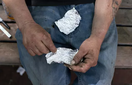A man prepares to smoke fentanyl on a park bench in downtown Portland, Ore., Thursday, May 18, 2023. Oregon is poised to step back from its first-in-the-nation drug decriminalization law. A measure lawmakers sent to the governor, Friday, March 1, 2024, would reinstate criminal penalties for possessing small amounts of some drugs. (Beth Nakamura/The Oregonian via AP)