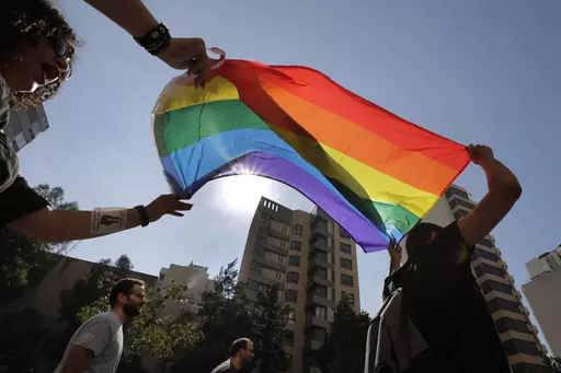 Activists from the Lesbian, Gay, Bisexual, and Transgender (LGBTQ) community in Lebanon shout slogans and hold up a rainbow demanding rights during a protest in Beirut, Lebanon, June 27, 2020. (AP Photo/Hassan Ammar, File)