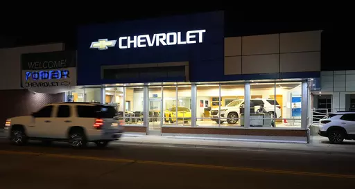FILE- A a vehicle passes a Chevrolet dealership in Fort Lupton, Colo. Many car shoppers neglect a key factor that can help save money: getting the best value for their trade-in vehicle. (AP Photo/David Zalubowski)