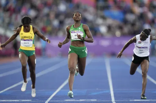 Favour Ofili of Nigeria, center crosses the finish line ahed of Natalliah Whyte of Jamaica, left, and Gina Bass of The Gambia, right, in a Women's 200 meters semifinal during the athletics competition in the Alexander Stadium at the Commonwealth Games in Birmingham, England, Friday, Aug. 5, 2022. Nigeria's national champion in the women's 100-meter sprint won't run the race at the Olympics because she says her country's track federation didn't enter her into the field in time. (AP Photo/Manish S