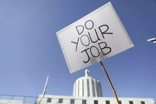 An attendee holds up a sign during a rally calling for an end to the Senate Republican walkout at the Oregon State Capitol in Salem, Ore., on May 11, 2023. Funding for schools, literacy programs and special education teachers in Oregon — a state where 60% of third graders are not reading at grade level — could be jeopardized by a Republican walkout that has stalled hundreds of bills and ground the Legislature to a partisan halt for over a month. (AP Photo/Amanda Loman, File)