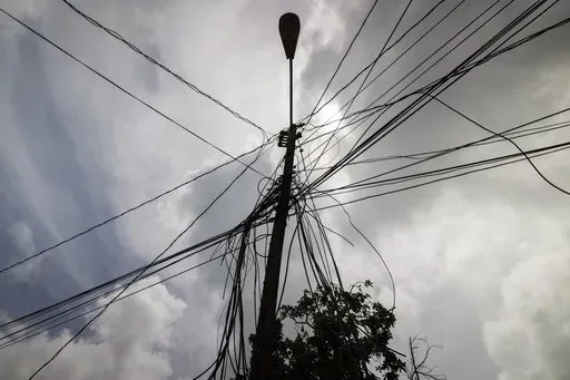 A utility pole with loose cables towers over a home in Loiza, Puerto Rico, Sept. 15, 2022. (AP Photo/Alejandro Granadillo, File)