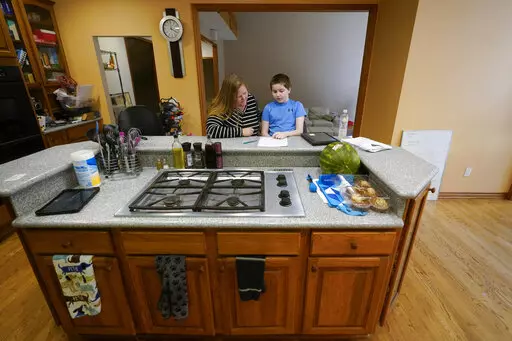 Lisa Manwell works on school work with her son John Jinks, 12, at their home in Canton, Mich., Wednesday, Sept. 21, 2022. Manwell says her son was improperly removed from his classroom last year because of behaviors that stemmed from his disability.  (AP Photo/Paul Sancya)
