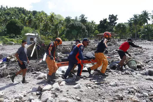 Rescuers carry a body at Maguindanao's Datu Odin Sinsuat town, southern Philippines on Sunday Oct. 30, 2022. Victims of a huge mudslide set off by Tropical Storm Nalgae in a coastal Philippine village that had once been devastated by a killer tsunami mistakenly thought a tidal wave was coming and ran to higher ground toward a mountain and were buried alive, an official said Sunday. (AP Photo)