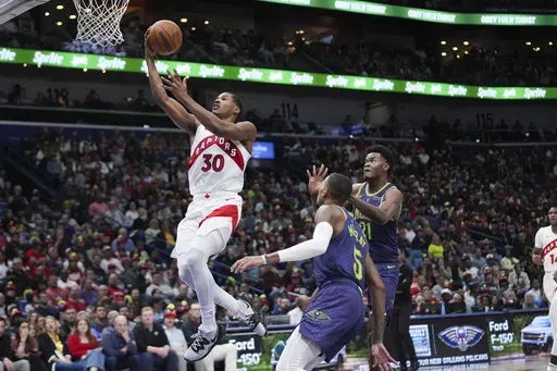 Toronto Raptors guard Ochai Agbaji (30) goes to the basket ahead of New Orleans Pelicans center Yves Missi (21) and guard Dejounte Murray (5) in the first half of an NBA basketball game in New Orleans, Wednesday, Nov. 27, 2024. (AP Photo/Gerald Herbert)