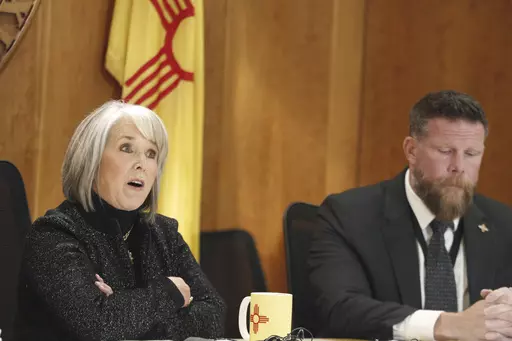 New Mexico Gov. Michelle Lujan Grisham, left, and Senior Public Safety Advisor Ben Baker, right, provide an update, Monday, Dec. 11, 2023, in Santa Fe, New Mexico, on a public health order aimed at reining in gun violence and drugs in the Albuquerque area that the governor describes as an epidemic. New Mexico could become an early political testing ground for a proposal to make assault-style weapons less deadly. (AP Photo/Morgan Lee)