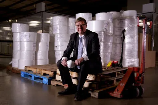 Jim Schmersahl, owner of Halcyon Shades, poses with material used in making N-95 masks Friday, March 18, 2022, in University City, Mo. Halcyon is small company that normally makes window shades, but when the pandemic hit, its sales plummeted. Halcyon applied for the state grants to make PPE as a way to try to keep its employees at work and keep the company afloat. (AP Photo/Jeff Roberson)