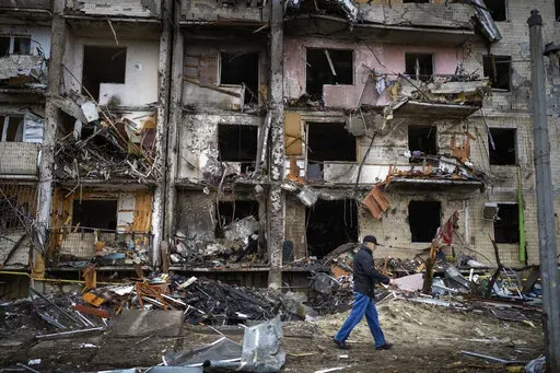 A man walks past a building damaged following a rocket attack, in Kyiv, Ukraine, Friday, Feb. 25, 2022.  The International Criminal Court's prosecutor has put combatants and their commanders on notice that he is monitoring Russia's invasion of Ukraine and has jurisdiction to prosecute war crimes and crimes against humanity. But, at the same time, Prosecutor Karim Khan acknowledges that he cannot investigate the crime of aggression. (AP Photo/Emilio Morenatti, File)