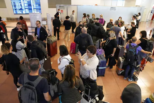 Foreign travelers gather upon arrival at the Haneda International Airport Tuesday, Oct. 11, 2022, in Tokyo. Japan's strict border restrictions are eased, allowing tourists to easily enter for the first time since the start of the COVID-19 pandemic. Independent tourists are again welcomed, not just those traveling with authorized groups. (AP Photo/Eugene Hoshiko)
