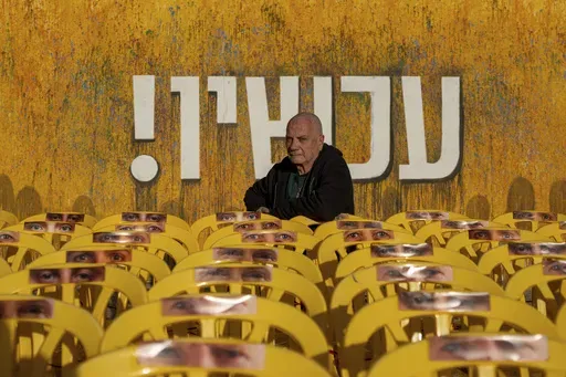 Luis Har, who was rescued from Hamas captivity in an Israeli raid last year, poses for a photo surrounded by empty chairs with photographs of other hostages' eyes, in Tel Aviv, Israel, Monday, Jan. 6, 2025. (AP Photo/Ohad Zwigenberg)