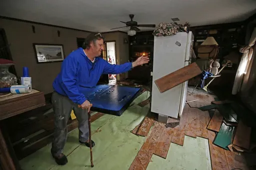 FILE-Jeff Sharp tosses flood-damaged flooring into a pile Feb. 19, 2020, as he helps his brother clean up after the Pearl River sent water into homes in Jackson, Miss. The U.S. Army Corps of Engineers in August 2024 is wrapping up a public comment period on its proposals for flood control measures in the Jackson area, and the agency could make final recommendations by the end of the year. (AP Photo/Rogelio V. Solis, File)