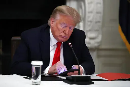 President Donald Trump looks at his phone during a roundtable with governors on the reopening of America's small businesses, in the State Dining Room of the White House in Washington, June 18, 2020. A San Francisco judge has rejected Trump's lawsuit challenging his lifetime ban from Twitter. U.S. District Judge James Donato said in a ruling Friday, May 6, 2022, that Trump's failed to show Twitter abridged his First Amendment right to free speech. (AP Photo/Alex Brandon, File)
