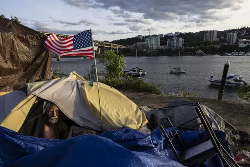 Frank, a homeless man, sits in his tent with a river view, June 5, 2021, in Portland, Ore. Momentum is building in a case regarding homeless encampments before the U.S. Supreme Court that could have major implications for cities as homelessness nationwide has reached record highs. (AP Photo/Paula Bronstein, File)