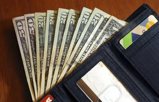 In this June 15, 2018, file photo, cash is fanned out from a wallet in North Andover, Mass. Spend enough time in the personal finance corners of social media and you’re bound to come across someone talking about how much passive income they make — and it’s likely they make it sound pretty easy.  (AP Photo/Elise Amendola, File)