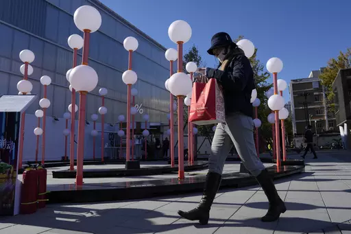 A shopper walks through a mall district in Beijing, Saturday, Nov. 11, 2023. Shoppers in China have been tightening their purse strings, raising questions over how faltering consumer confidence may affect the annual Singles' Day online retail extravaganza. (AP Photo/Ng Han Guan)