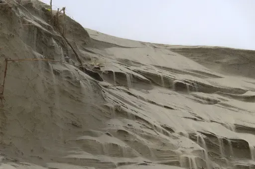 Sand cascades down the badly eroded face of a dune in North Wildwood, N.J. on Feb. 24, 2023. (AP Photo/Wayne Parry, FILE)