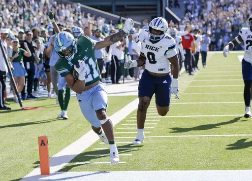 Tulane running back Makhi Hughes (21) scores on a 29-yard pass from quarterback Darian Mensah (10) as Rice defensive lineman Joseph Mutombo (8) gives chase during the first half of an NCAA football game at Yulman Stadium in New Orleans, Saturday, Oct. 19, 2024. (Scott Threlkeld/The Times-Picayune/The New Orleans Advocate via AP)