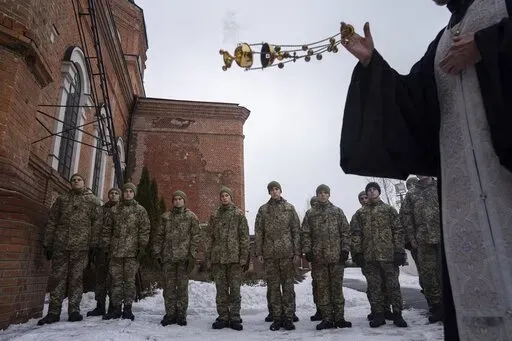 An Orthodox priest blesses Ukrainian Military Air Force University cadets after a monthly memorial service for soldiers who were killed during the fighting against Russia-backed separatists in eastern Ukraine, in Kharkiv, Ukraine, Thursday, Feb. 3, 2022. Russia maintains it has no intention to attack its neighbor, but demands that NATO won't expand to Ukraine and other ex-Soviet nations or deploy weapons there. It also wants the alliance to roll back its deployments to Eastern Europe. (AP Photo/
