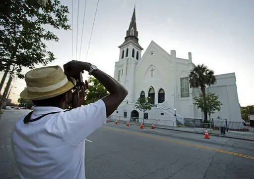 FILE _ This file photo shows Ausar Vandross taking a photo of Mother Emanuel AME Church in Charleston, S.C., on Thursday, June 16, 2016. The church is among those that have been assisted by a fund to help historic Black churches, and a new, $20 million donation will help additional ones. (AP Photo/Chuck Burton)