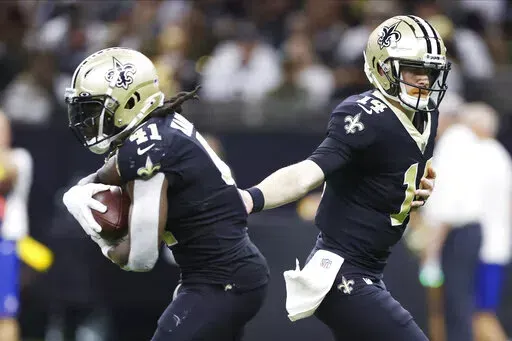New Orleans Saints quarterback Andy Dalton (14) hands off the ball to running back Alvin Kamara (41) during the second half of an NFL football game against the Las Vegas Raiders Sunday, Oct. 30, 2022, in New Orleans. (AP Photo/Rusty Costanza)