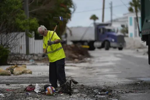 Teams work to clean up piles of debris from Hurricane Helene flooding ahead of the arrival of Hurricane Milton, in Holmes Beach on Anna Maria Island, Fla., Tuesday, Oct. 8, 2024. (AP Photo/Rebecca Blackwell)