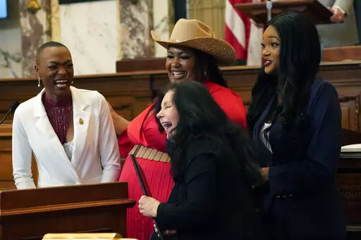 State Sen. Angela Hill, R-Picayune, foreground, laughs with members of the country music harmony group, Chapel Hart, as she presents them with a resolution on the Senate floor at the Mississippi Capitol in Jackson, Miss., Wednesday, Jan. 4, 2023. The group's members, Trea Swindle, left, her cousins Danica Hart, center, and her sister Devynn Hart, are from Poplarville, and made national entertainment headlines when they made the finals of a national talent show. (AP Photo/Rogelio V. Solis)