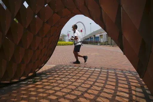 A man jogs in a park in Hong Kong, Thursday , May 5, 2022. Hong Kong on Thursday reopened beaches and pools in a relaxation of COVID-19 restrictions, while China's capital Beijing began easing quarantine rules for arrivals from overseas. (AP Photo/Kin Cheung)