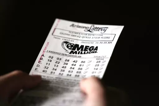 A person holds a Mega Millions lottery ticket in Tempe, Ariz., Friday, Dec. 30, 2022. The jackpot for the Friday drawing is estimated at $640 million. (AP Photo/Ross D. Franklin)