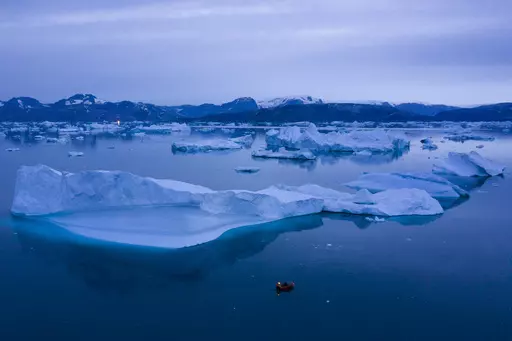 A boat navigates at night next to large icebergs near the town of Kulusuk, in eastern Greenland on Aug. 15, 2019. A new massive study finds that Greenland and Antarctic ice sheets are now losing more than three times as much ice a year as they were 30 years ago. (AP Photo/Felipe Dana, File)