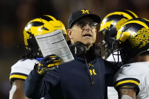 Michigan head coach Jim Harbaugh stands on the field during the first half of an NCAA college football game against Minnesota Saturday, Oct. 7, 2023, in Minneapolis. The NCAA banned in-person advanced scouting in 1994 in part because not every school could afford to do it. Now Michigan is being investigated by the NCAA for a sign-stealing scheme that allegedly involved people secretly being sent to record opponents’ games. No. 2 Michigan and the Big Ten acknowledged the investigation Thursday,