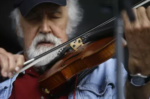 Michael Doucet performs with the Cajun band BeauSoleil at the New Orleans Jazz and Heritage Festival in New Orleans, Friday, May 3, 2013. Cajun fiddler Doucet fell and broke his hip in Alaska, and his Grammy-winning band had to perform there without him. His brother, guitarist David Doucet, wrote about the accident Saturday, April 2, 2022, on his Facebook page and reposted the message on the page for the band, Beausoleil avec Michael Doucet. (AP Photo/Gerald Herbert, File)