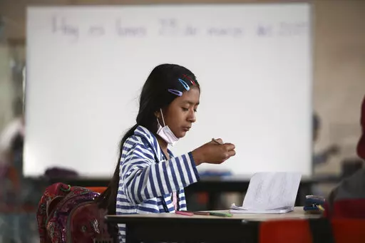 A student focuses on her lesson at Casa Kolping, an alternative education center where child migrants from two pastor-run shelters take classes every weekday morning, in Ciudad Juarez, Mexico, on Monday, March 28, 2022. Education is a big challenge for children on their migration journey, but opportunities like this give them a chance to catch up on academics and to find emotional support. (AP Photo/Christian Chavez)