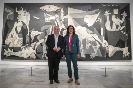 French Culture Minister Rima Abdul-Malakin, right, poses for a picture next to his Spanish counterpart Miquel Iceta during a joint news conference in front of Pablo Picasso's "Guernica" painting to present the "Picasso Year" events, marking the 50th anniversary of the painter's death, at the Reina Sofia Museum in Madrid, Spain, Monday, Sept. 12, 2022. Against the backdrop of Picasso's iconic anti-war painting, "Guernica," the culture ministers of France and Spain have gathered in Madrid to kick 
