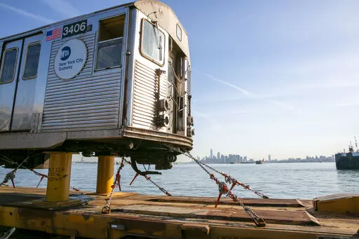 One World Trade Center in Manhattan is visible from a railroad barge carrying retired 1960s-era R-32 subway cars through New York Harbor in New York, on Wednesday, June 15, 2022. Crews are taking the old subway cars to an Ohio scrapyard as the MTA installs new R-179 train cars into the city's sprawling subway system. (AP Photo/Ted Shaffrey)