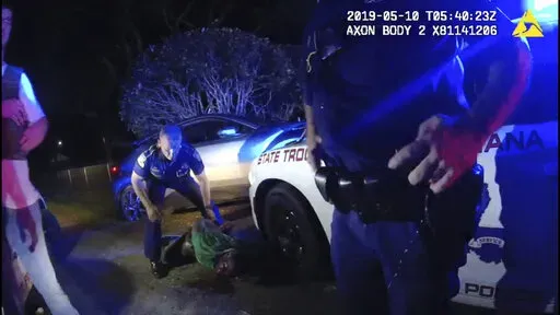 In this image from the body video camera of Louisiana State Police Lt. John Clary, Trooper Kory York stands over Ronald Greene, lying on his stomach, outside of Monroe, La., on May 10, 2019. (Louisiana State Police via AP)