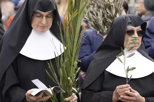 Nuns wait for the start of the Palm Sunday's mass celebrate by pope Francis in St. Peter's Square at The Vatican Sunday, April 2, 2023. Palm Sunday will be celebrated by Christians worldwide Sunday, March 24, 2024. It commemorates the Christian belief in the triumphant entry of Jesus into Jerusalem, when palm branches were strewn before him. It marks the start of Holy Week. (AP Photo/Andrew Medichini)