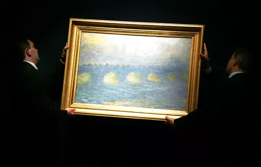 Two staff hang a Claude Monet 1904 painting 'Waterloo Bridge, temps couvert', for display at Christie's in London, Thursday, June 14, 2007. The painting was one of 60 pieces from the Paul G. Allen collection auctioned by Christie's in New York, on Wednesday, Nov. 9, 2022, bringing $1.5 billion in a single night. It sold for $64.5 million. (AP Photo/Sang Tan, File)